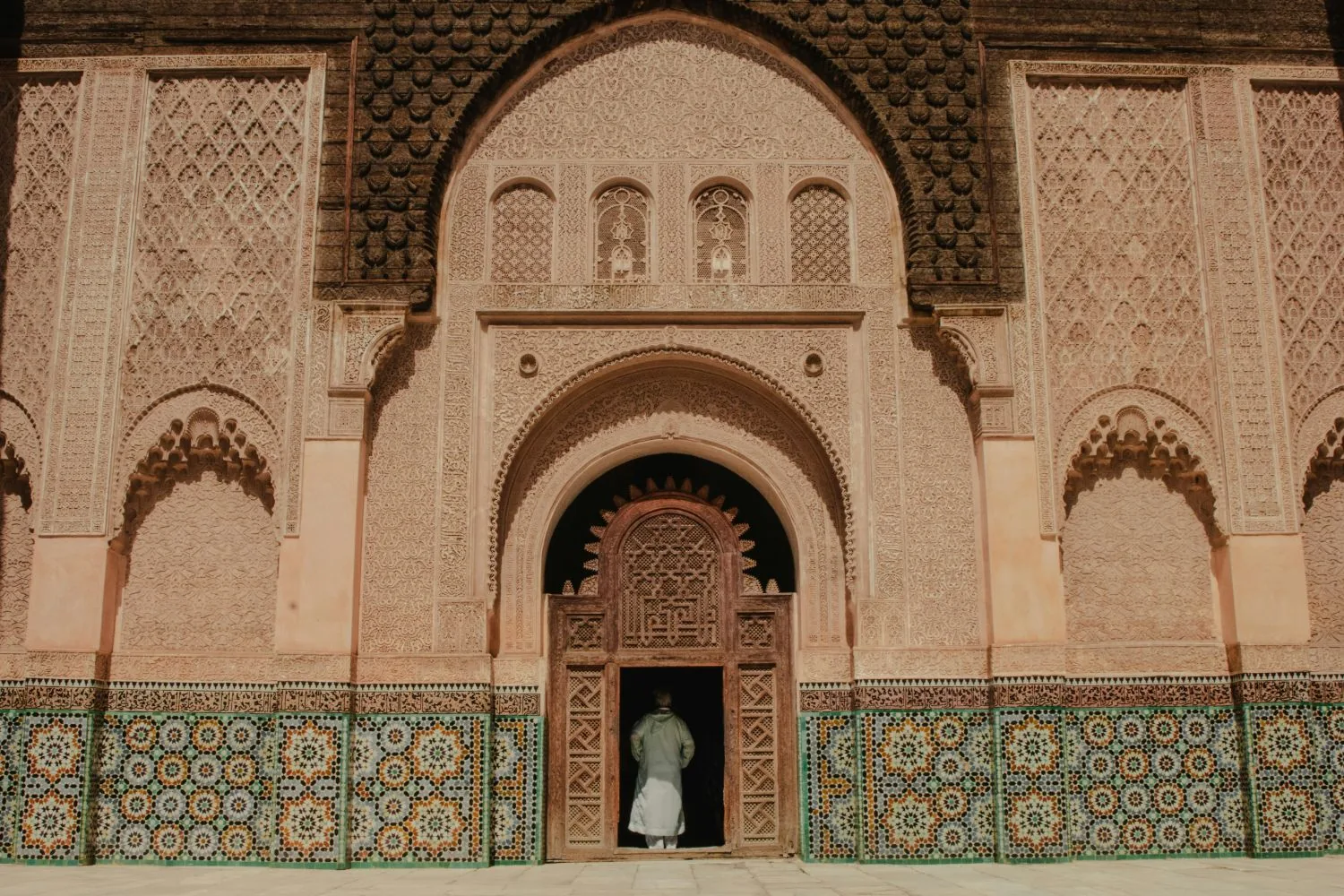 Façade ornée de la médersa Ben Youssef à Marrakech, avec sa porte en bois sculpté et ses zelliges